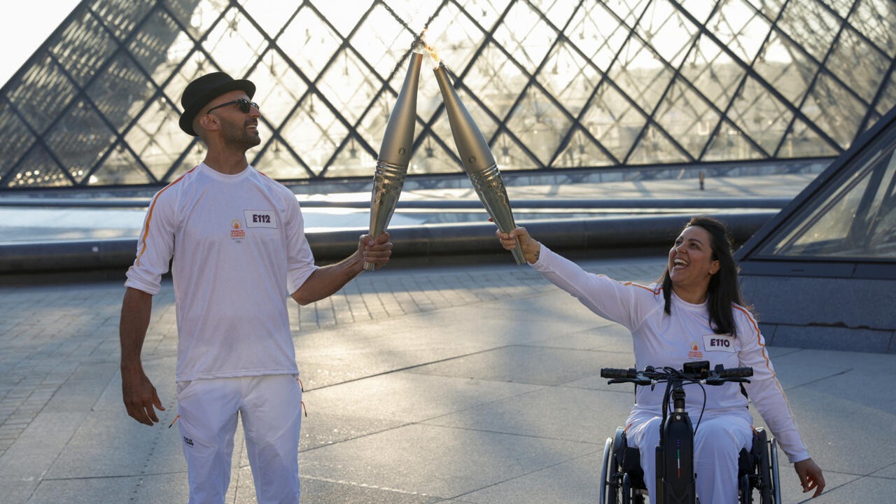 L'artiste JR aux côtés de la skieuse Sandra Laoura font la passation de la flamme olympique, le 14 juillet 2024.